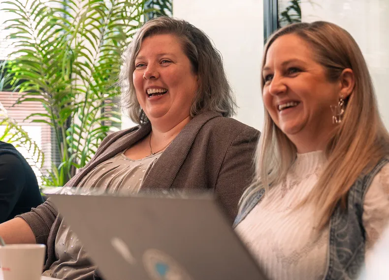 twee vrouwelijke collega's aan het lachen tijdens een gesprek