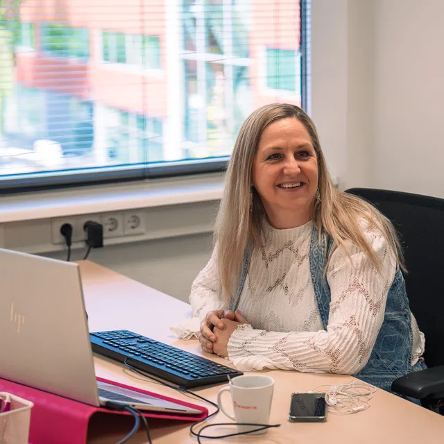vrouw aan het lachen achter haar bureau