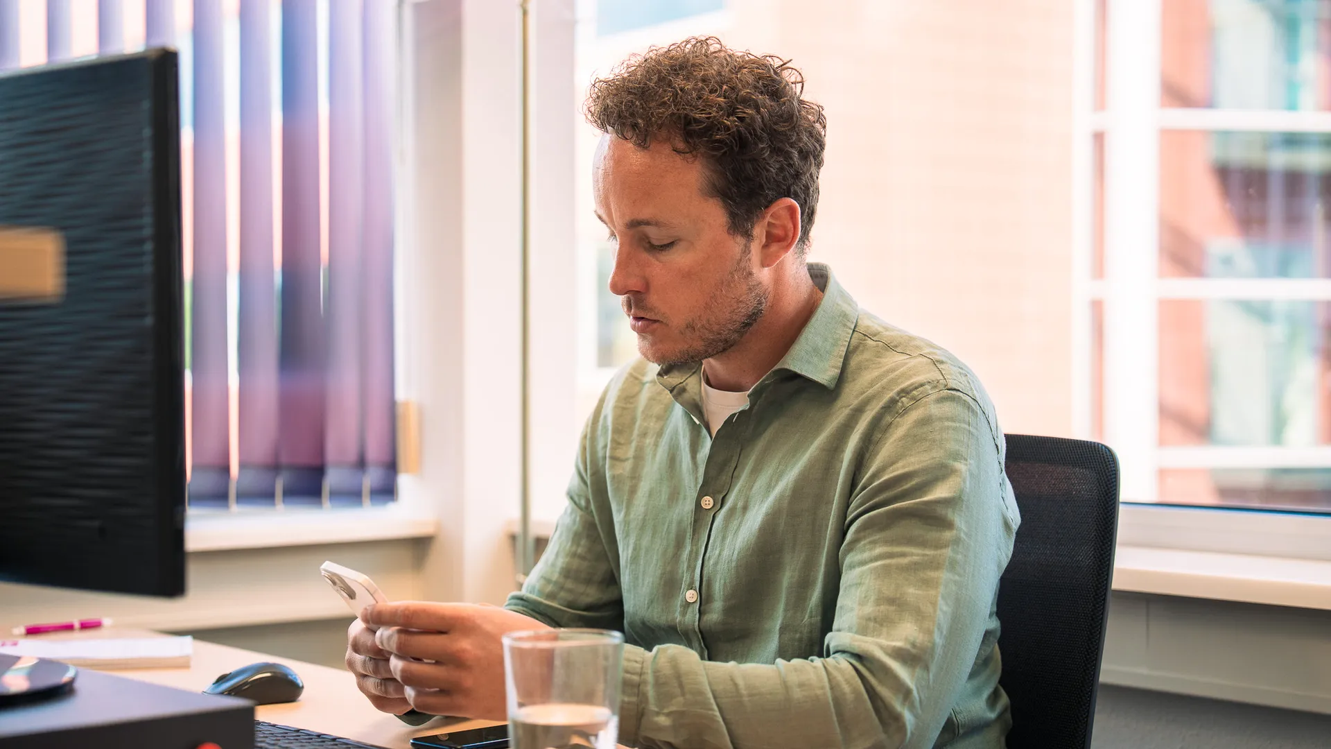 man aan het telefoneren achter zijn bureau