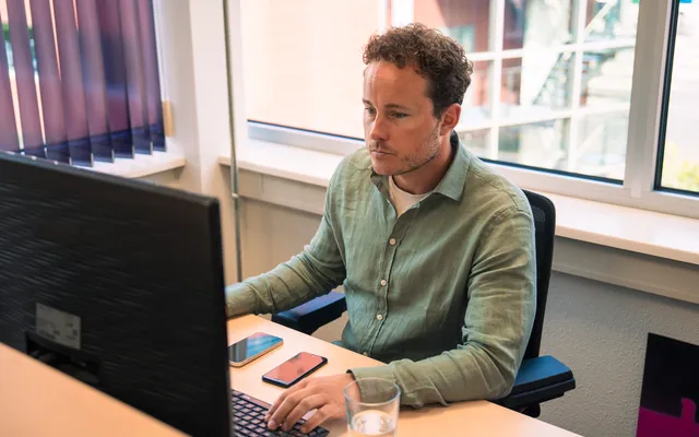 man achter zijn bureau aan het werk in een kantoorruimte