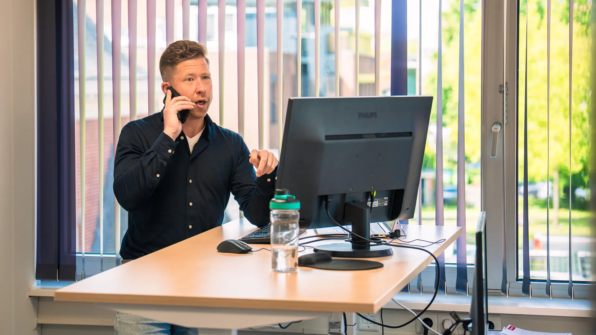 man aan het bellen achter zijn bureau