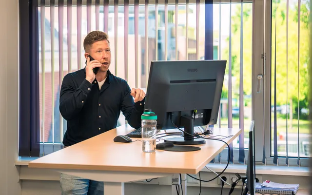 man aan het bellen achter zijn bureau