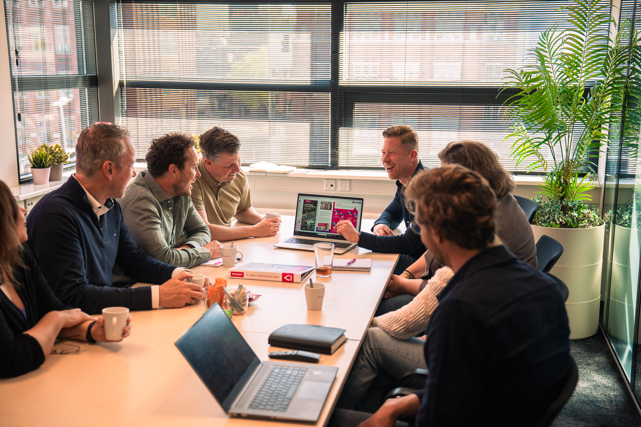 teamfoto met lachende mensen aan een vergadertafel