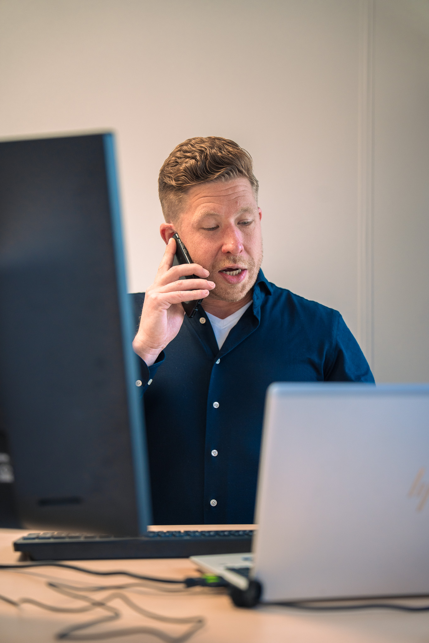 man aan het bellen achter zijn bureau